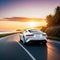 A white car drives off into the sunset along the road to the ocean