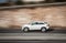 White car moving fast along the street on a motion blurred background.