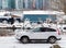 A white car parked outdoor on a street on a snowy winter day