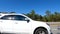 A white car passes by in slow motion clear blue sky and nature background
