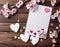 White card with white hearts and sakura branches on a wooden surface