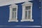 White carved architraves on the Windows of a blue wooden house