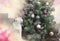 A white cat with black and red spots on its back and head sits on a sofa and looks at the Christmas tree, New Year\\\'s cozy