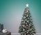 A white cat with black and red spots on its back and head sits on a sofa next to a beautiful Christmas tree, New Year\\\'s cozy