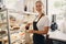 white Caucasian beautiful barista woman taking muffin pastry from shop-window.