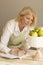 White caucasian blonde matured woman makes notes in notebook (planner) and looks at edible fresh bouquet