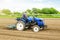 A white caucasian farmer on a tractor making rows on a farm field. Preparing the land for planting future crop plants. Cultivation