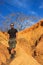 White Caucasian male traveler in sportswear: boots, shorts, wearing glasses stands against the bright yellow rocks in Kenya