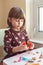 White Caucasian preschooler girl playing plasticine playdough indoors at home