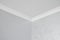 White ceiling with a white plinth in a room with gray painted walls. Decoration of the corner between the ceiling and