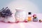 White ceramic candle aroma oil lamp with essential oil bottle and dried flowers, crystal geodes on modern pastel pink and blue bac