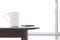 White ceramic coffee cup and smart phone on oval wooden table with blurred frosted glass sliding door in living room