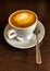 White ceramic cup with  saucer with aromatic cappuccino coffee, with airy beautiful brown foam, and  small dessert shiny spoon, on