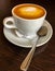 White ceramic cup with  saucer with aromatic cappuccino coffee, with airy beautiful brown foam, and  small dessert shiny spoon, on