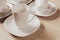 White ceramic cups and plates on wooden background, image