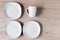 White ceramic cups and plates on wooden background, image