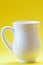 White ceramic milk jug on yellow background