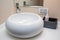 White ceramic oval round washbasin for bathroom. White bathroom with round mirror and white ceramic wash basin. Modern Ceramic
