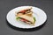 White ceramic plate with two sandwiches with feta, tomato, lettuce and olive pate
