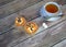 White ceramic tea cup on a saucer with a spoon and a napkin with two fresh muffins and cubes of sugar on a wooden table