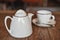 White ceramic teapot and a Cup of invigorating fresh fragrant tea on a brown wooden table