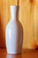 White ceramic vase small close up, stands on a wooden background decor