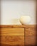 White ceramic vase on a wooden chest of drawers