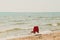 White chair with red cover standing at the summer beach in front of sea and couple in love in the water