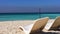 White chaise longue on sandy beach and splashing sea waves