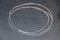 White chalk hand drawing in circle or oval shape on black board background