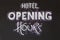 White chalk sign writing reading "Hotel Opening Hours"