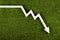 White chart arrow on green grass pointing down. Business loss symbol, ecology concept, green energy spending.