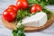 White cheese, knife, parsley, tomatoes on a wooden boards background