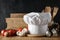 White chef`s hat and wooden table background with dark wall and kitchen utensils..