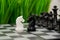 A white chess knight stands in front of a black one and an army of black chess pieces. The concept of confrontation and
