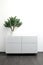 White chest of drawers with flower pot in bright interior