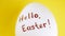 White chicken egg with black text on it - hello easter on yellow