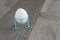 White chicken egg in blue funny stand on wooden background. Easter decor.