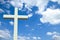 White Christian cross in front of a cloudy sky