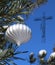 White Christmas ball on real live outdoor Christmas tree with semi-transparent crucifix
