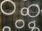 White circular ring shaped lamps hang under a concrete ceiling