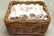 White clean rolled terry towel stack in wicker basket on natural wooden background. Close up