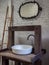 White clean sink bath and faucet on vintage wooden table and vintage mirror on white brick wall background