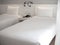 White clean twin bed with white pillows in hotel bedroom