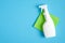 White cleaner spray bottle and green rag on blue background. Flat lay, top view. House cleaning service and housekeeping concept