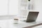 white and clear office room with laptop and coffee on table