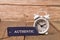 White clock and label tag written with AUTHENTIC on wooden board