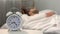 White clock near sleeping man bed, healthy morning habit, biorhythms, jet lag