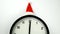 The white clock in red sunta hat shows five to seconds midnight, on the blurry background. Countdown to the new year