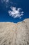 A white cloud in a blue sky over a desolate arid area
